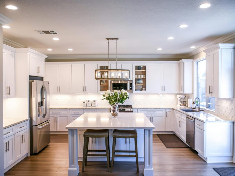 Spacious and elegant kitchen featuring white cabinetry, island, and stainless steel appliances.